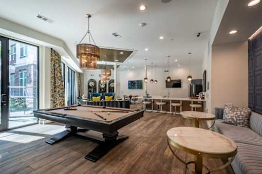 A billiard table is in the middle of a room with a couch and a table.