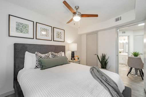 A bedroom with a large bed and a ceiling fan.