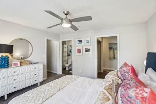 A bedroom with a white bed and a white dresser with a mirror.