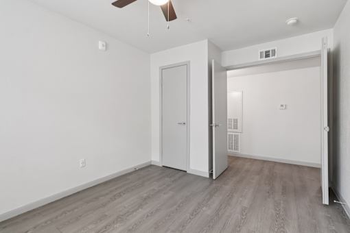 A room with a white door and a ceiling fan.