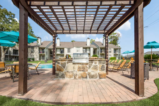 a backyard with a grill and a pool with umbrellas
