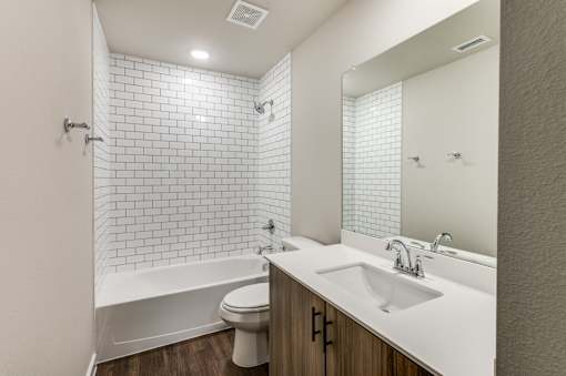 A white bathroom with a white toilet, white sink, and white tiles.