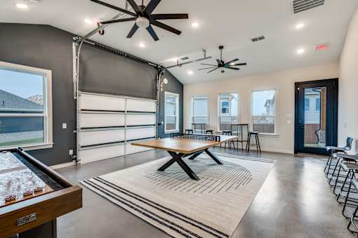 A room with a foosball table and a long table with chairs.