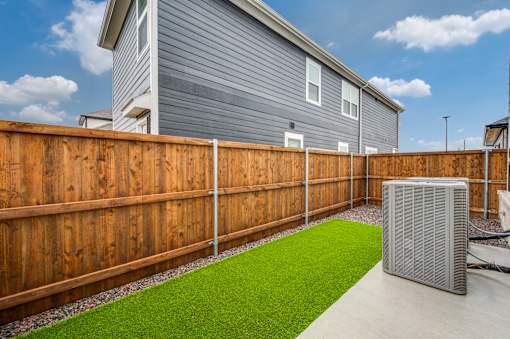 A backyard with a wooden fence and a green lawn.
