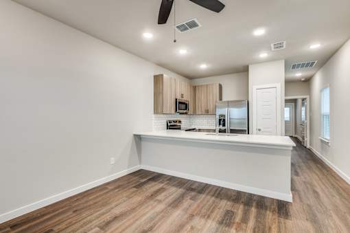 A spacious kitchen with wooden floors and white walls.
