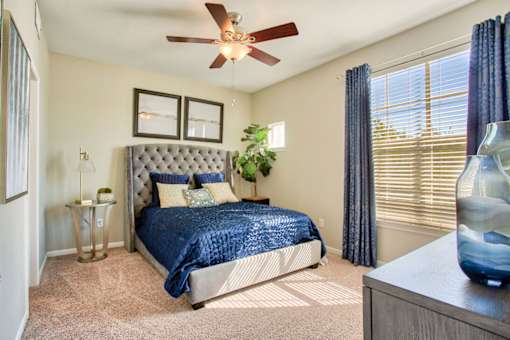 A bedroom with a bed, a ceiling fan, and a nightstand.