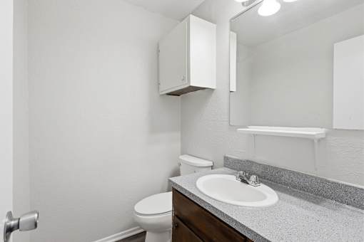 A bathroom with a toilet, sink, and medicine cabinet.