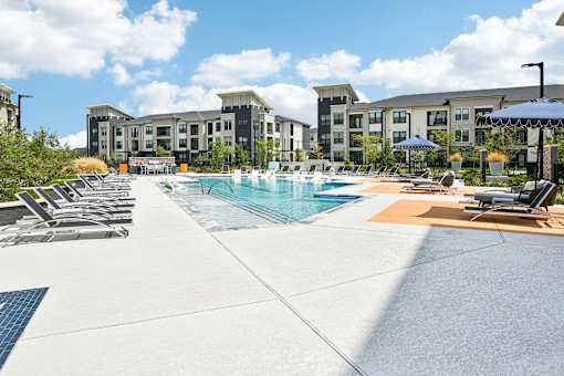 A pool area with sun loungers and a building in the background.