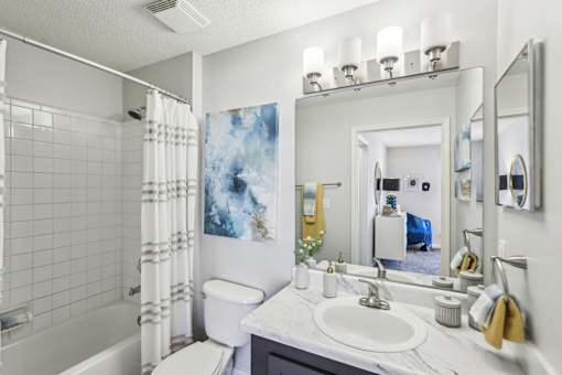 A bathroom with a white sink, toilet, and a white tiled shower.