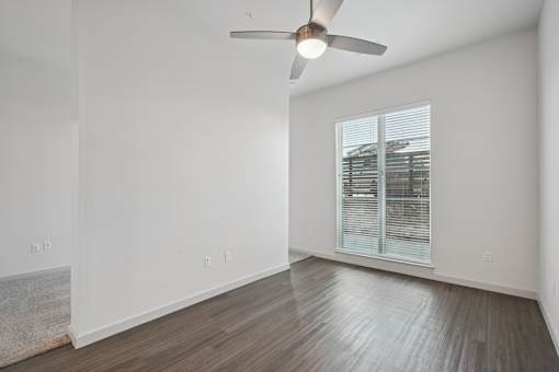 A room with a ceiling fan and a window with blinds.
