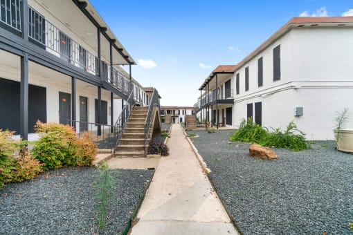 a courtyard between two buildings with a dog laying on the ground