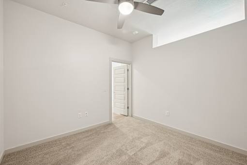 A room with a carpeted floor and a ceiling fan.