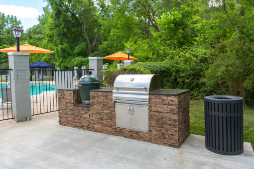 a bbq area with a grill and a trash can in a backyard