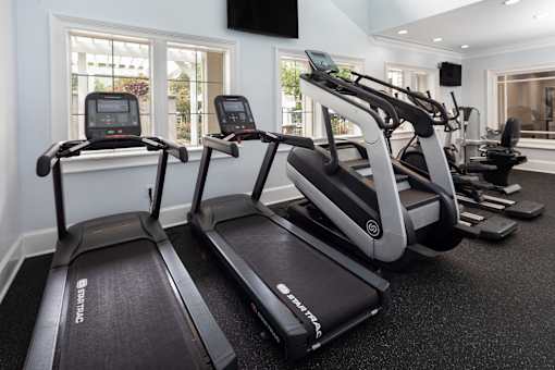 A treadmill and a stationary bike are in a well-lit room.