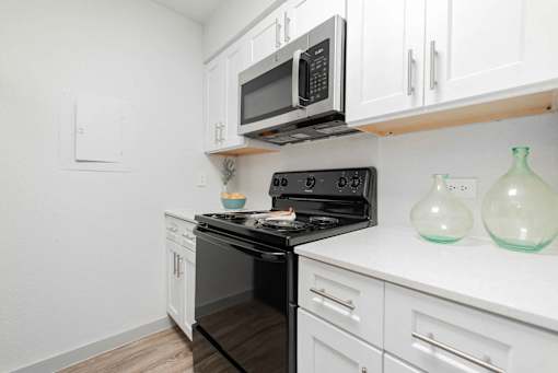 A black stove top oven with a black microwave above it.