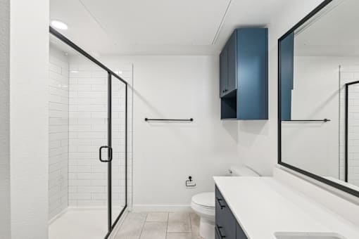 A white bathroom with a toilet, sink, and a walk-in shower.
