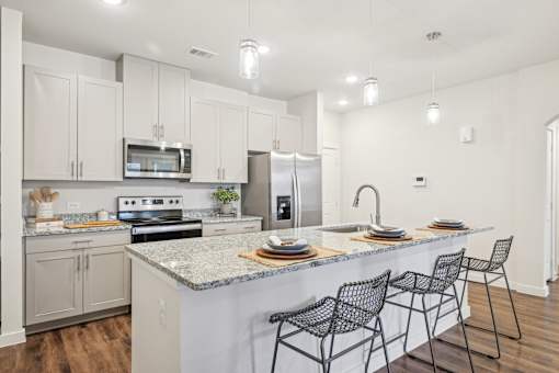 A kitchen with a white counter top and black chairs.
