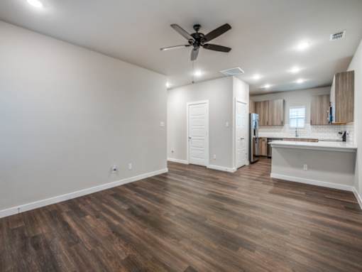A room with a ceiling fan and wooden flooring.