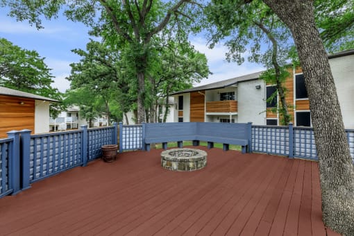 a large deck with a firepit and a blue fence