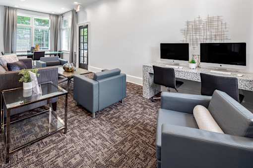 A living room with a grey couch, a glass coffee table, and a TV on a desk.