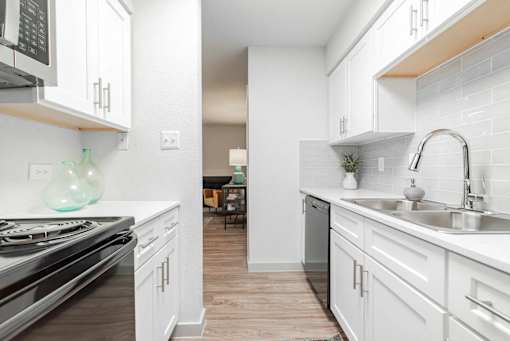A kitchen with white cabinets and a stove top oven.