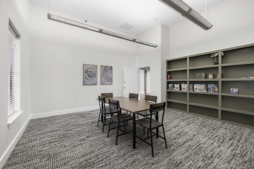 A room with a table and chairs and a shelf with books.