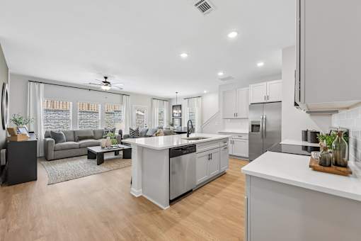 A modern kitchen with a large island and a living area with a couch.