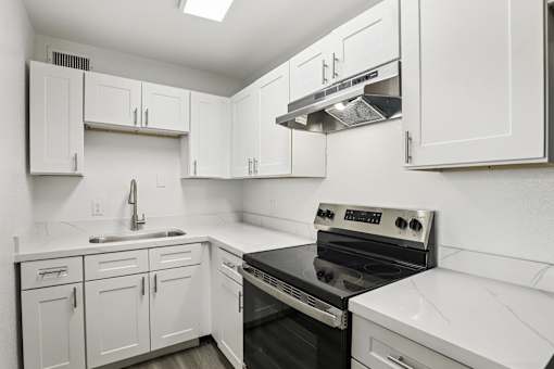 A kitchen with white cabinets and a black stove top oven.