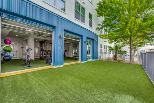 a home gym with a green lawn and a building with blue doors