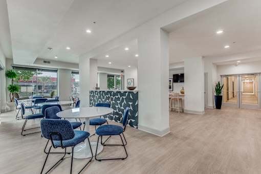 A modern dining room with a white table and blue chairs.