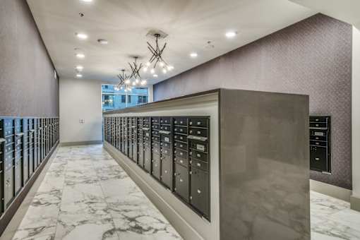A long hallway with a marble floor and a wall of elevators.