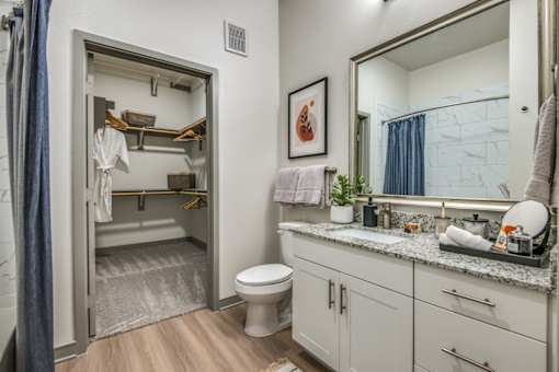 A bathroom with a toilet, sink, and mirror.