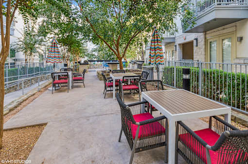 A patio with a table and chairs is surrounded by a fence and trees.