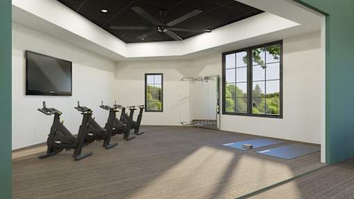 A room with a row of stationary bikes and a television mounted on the wall.