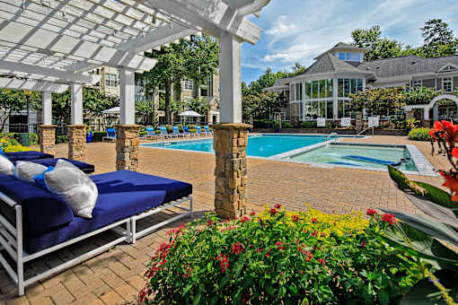 A pool area with sun loungers and a white pergola.