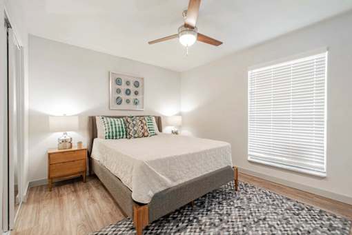 A bedroom with a bed, nightstand, and a ceiling fan.