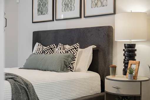 A bed with a grey headboard and a grey pillow is in the image.