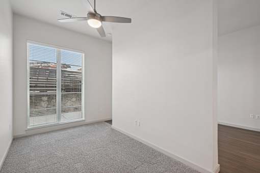 A room with a ceiling fan and a window with blinds.