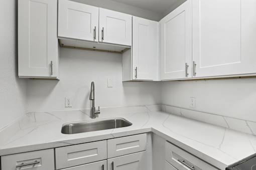 A kitchen with white cabinets and a sink.