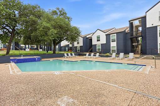 A swimming pool surrounded by a fence and chairs.