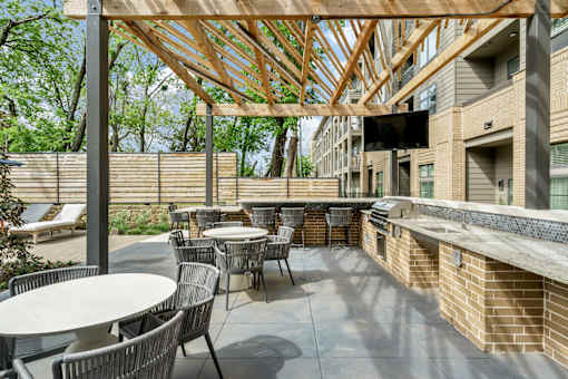 A patio with tables and chairs under a wooden roof.
