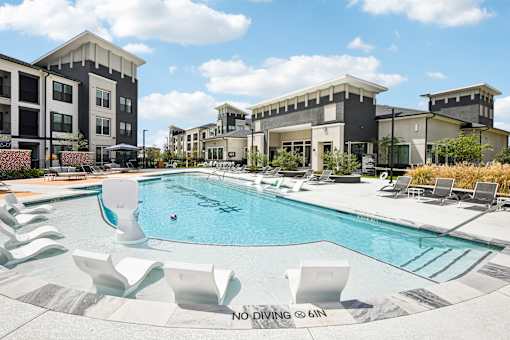 A pool with chairs around it and a sign that says "NO DIVING @ 6IN".