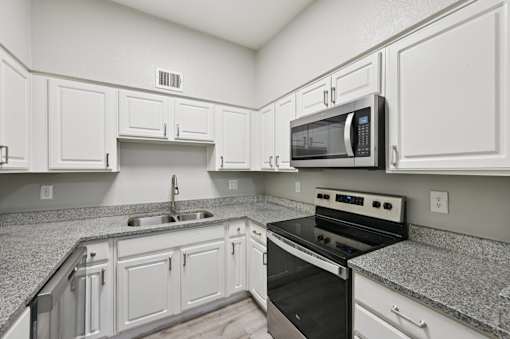 A kitchen with white cabinets and granite countertops.