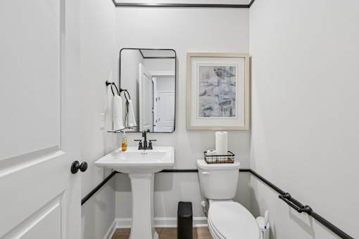 A bathroom with a toilet, sink, and mirror.
