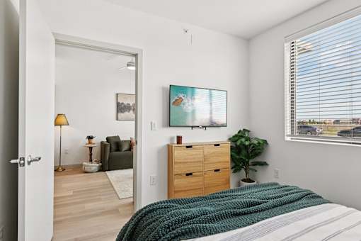 A bedroom with a bed, dresser, and a painting on the wall.