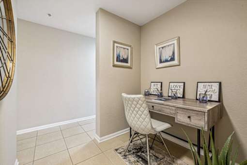 A white chair is in front of a desk with a mirror above it.