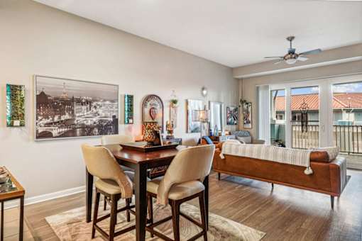 A dining room with a table and chairs and a picture on the wall.