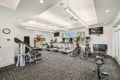 A spacious gym with a variety of equipment including treadmills, stationary bikes, and weight machines.