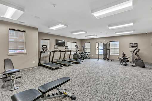 A spacious gym with a variety of equipment including treadmills, elliptical machines, and weight machines.