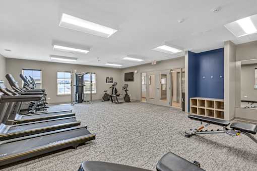 A spacious gym with treadmills, elliptical machines, and a weight room.
